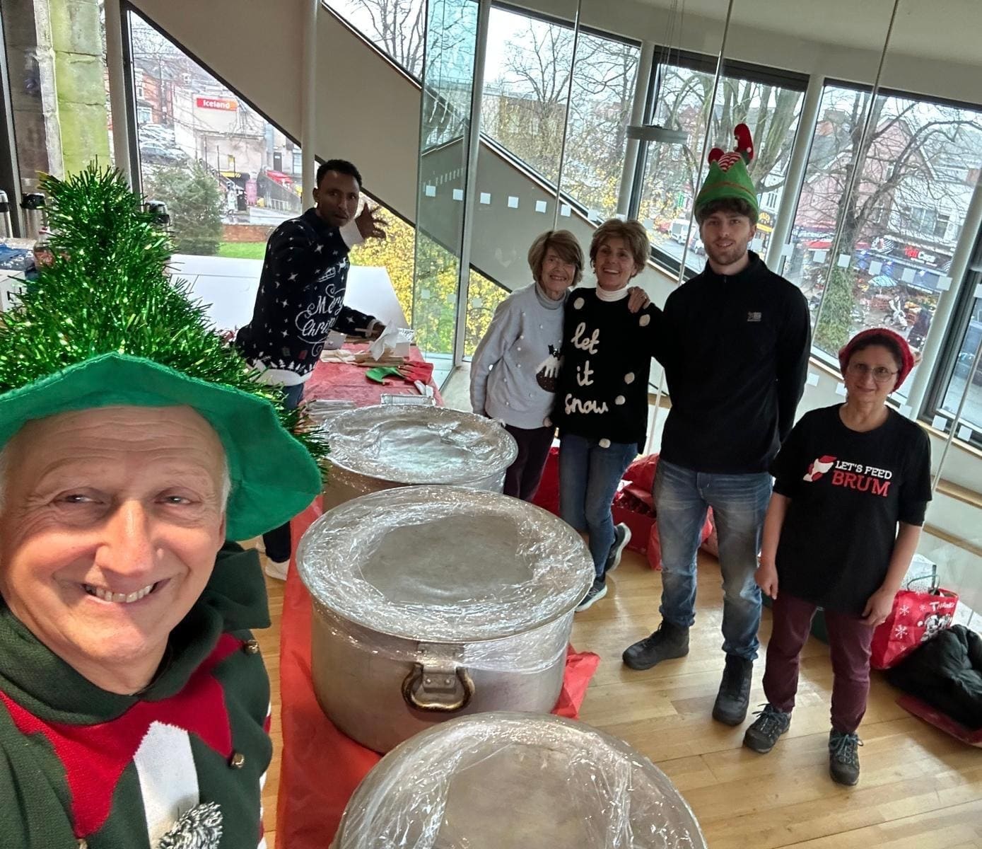 Let's Feed Brum volunteers in Christmas jumpers and elf hats, ready beside the covered cooking pots