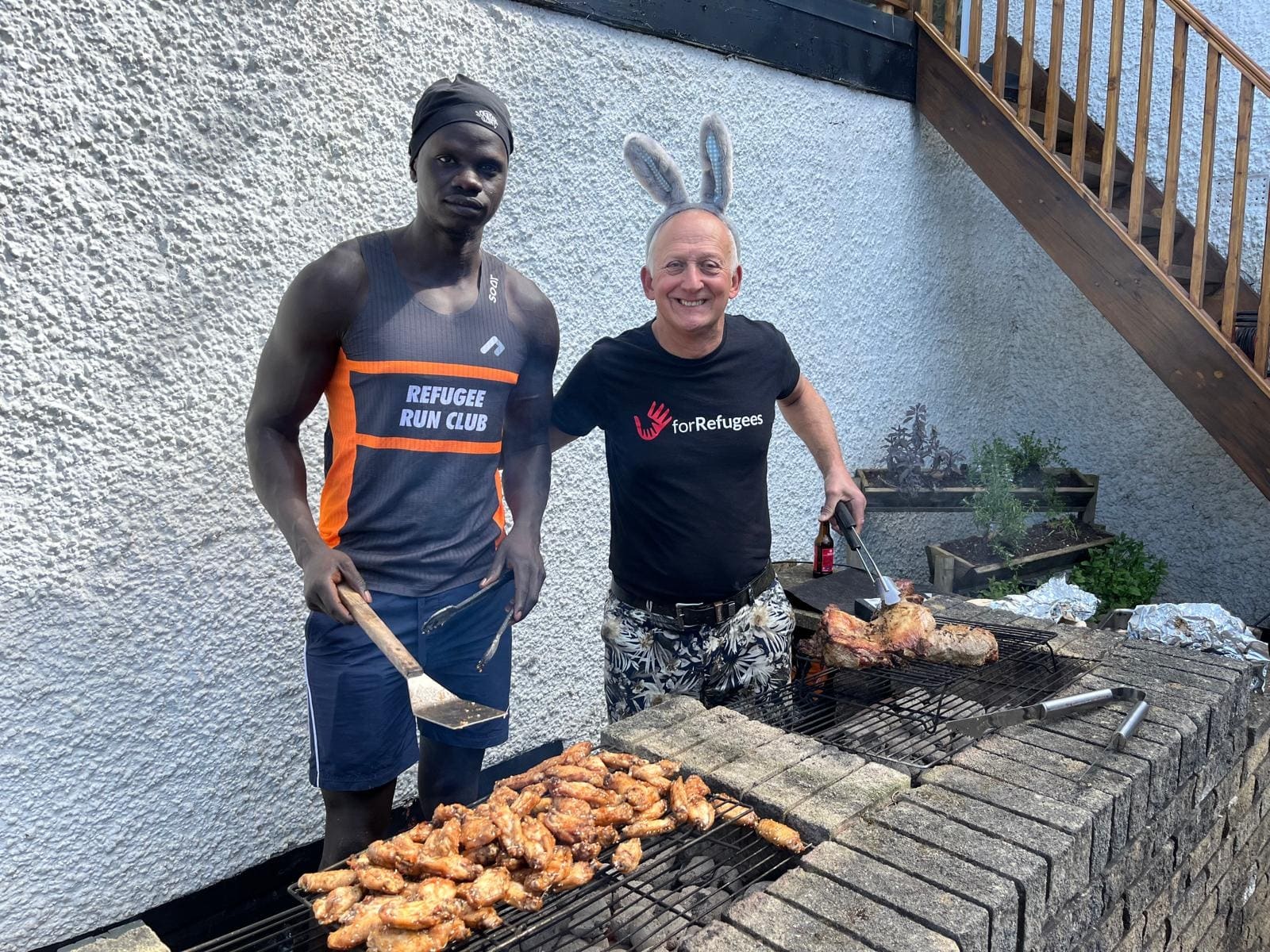 Chicken on the barbecue, with a Refugee Run Club member at the grill