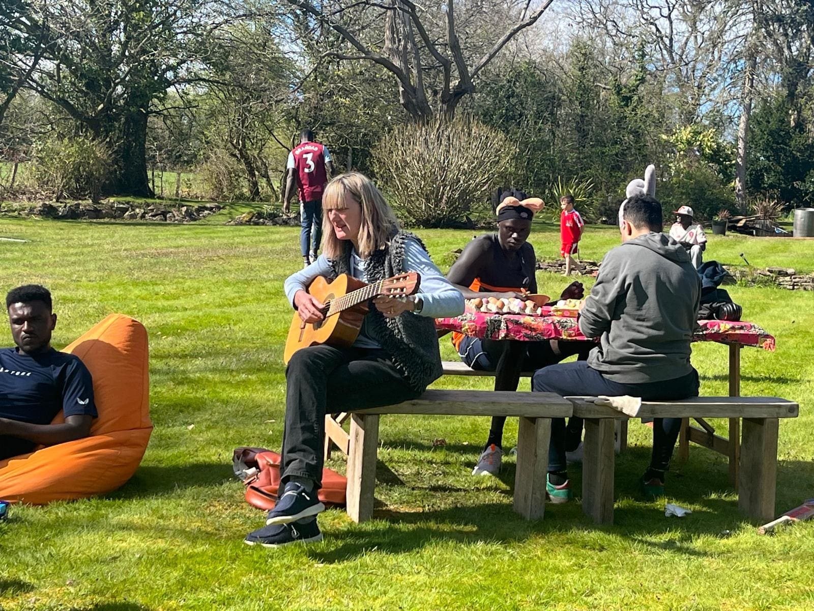 Playing guitar at a picnic bench on the lawn
