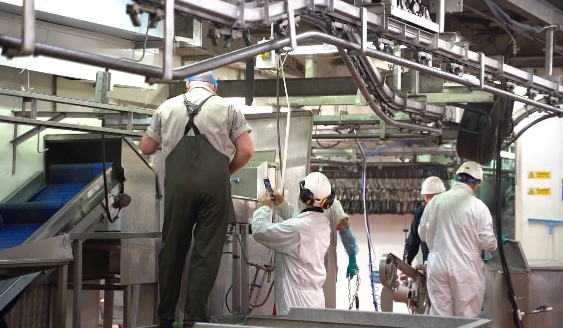Staff in white overalls and hard hats at work in the processing plant